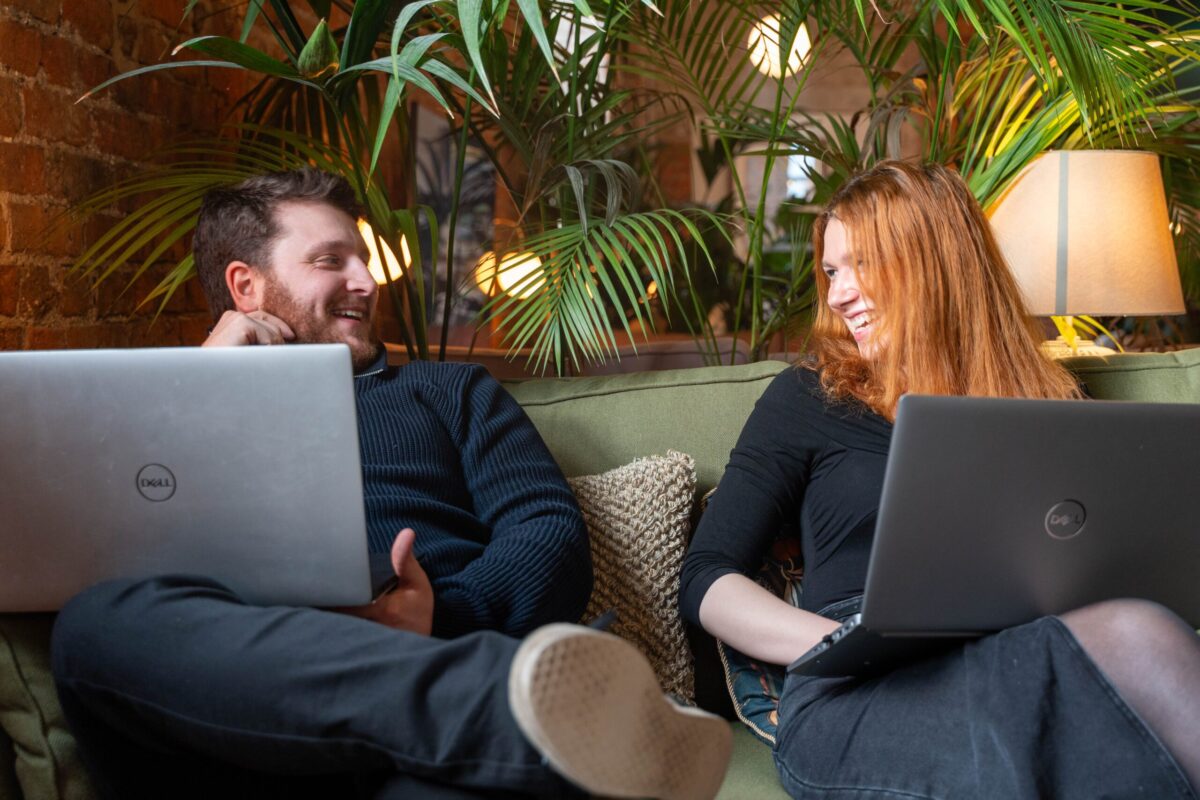 Ashley and Daniela with laptops on a sofa