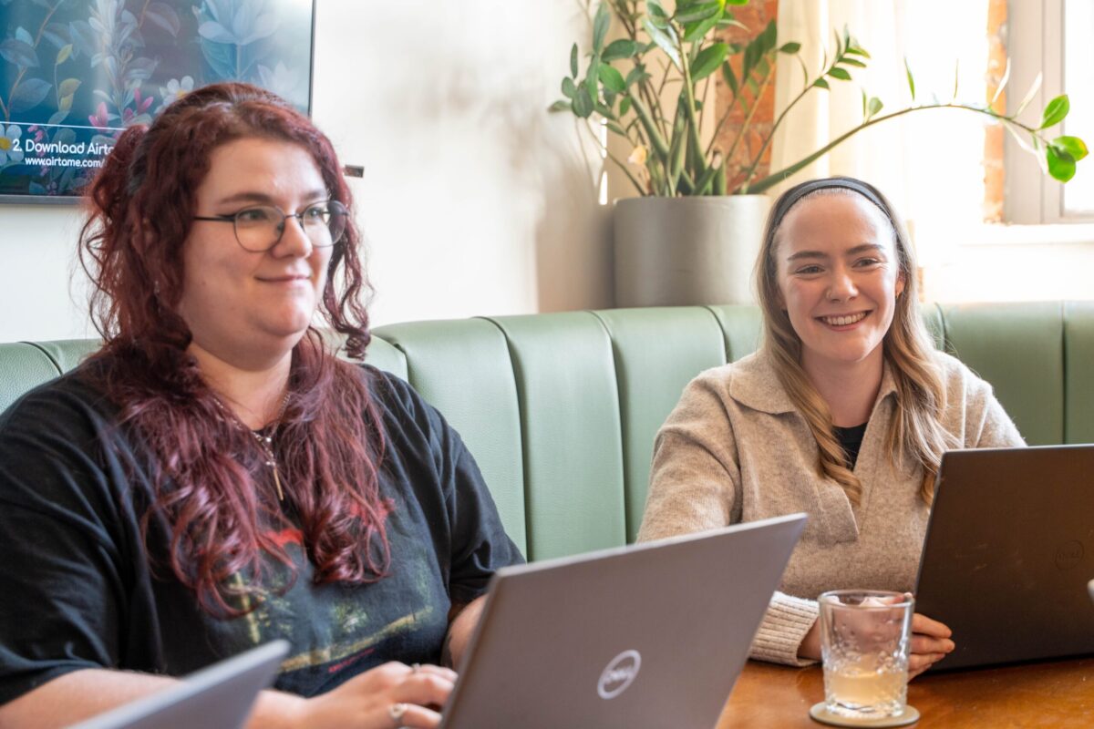 Kestra and Eve sat in a meeting room with laptops